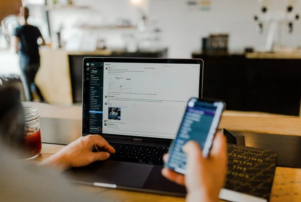 A person with their laptop open to a messaging service as well as messages on their phone